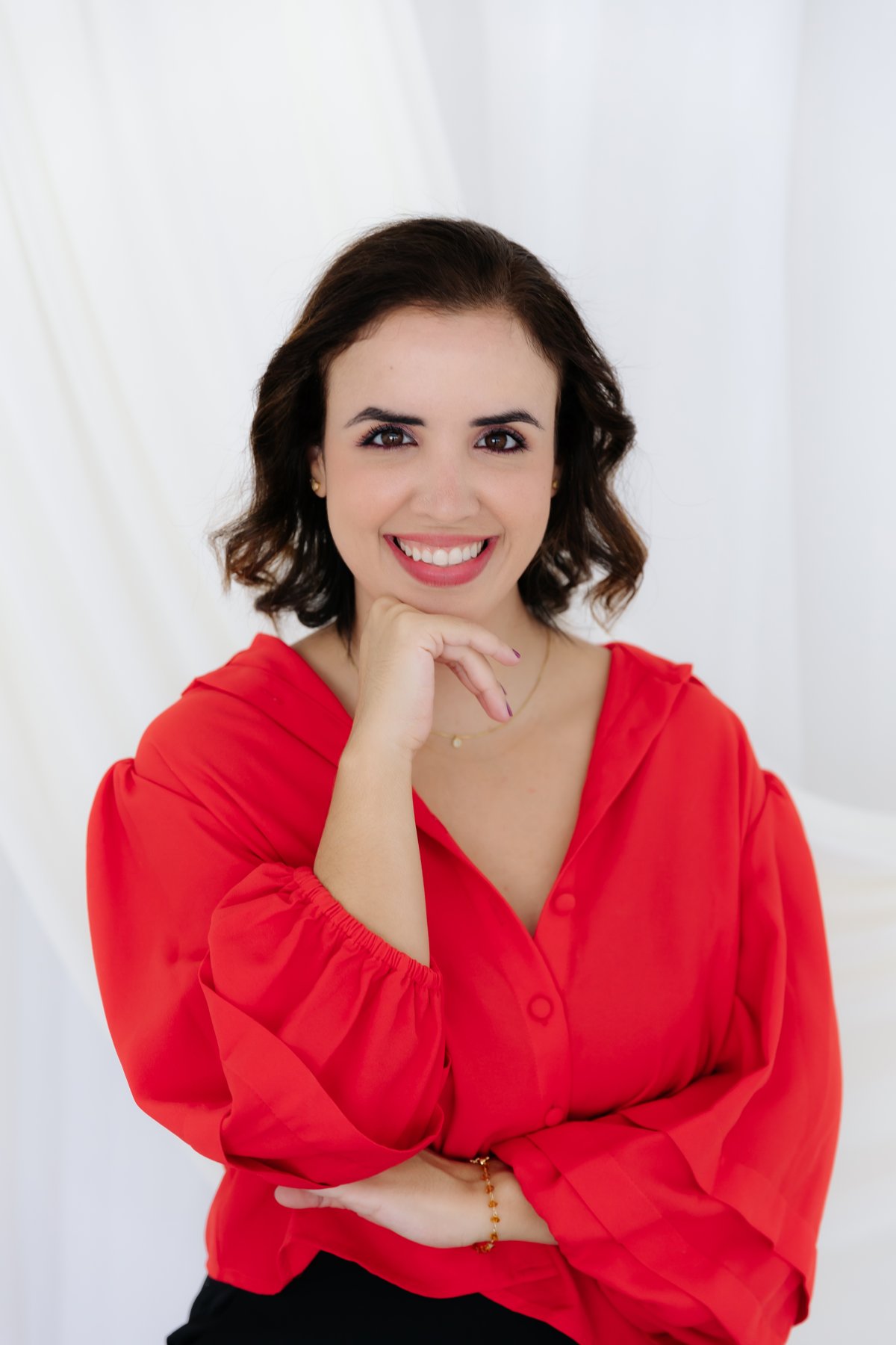 Foto de Amanda Moraes, professora de idiomas e mentora de professores, sorrindo com a mão no queixo